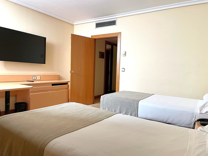 Modern hotel room at AR: Parquesur featuring two twin beds and a workspace.