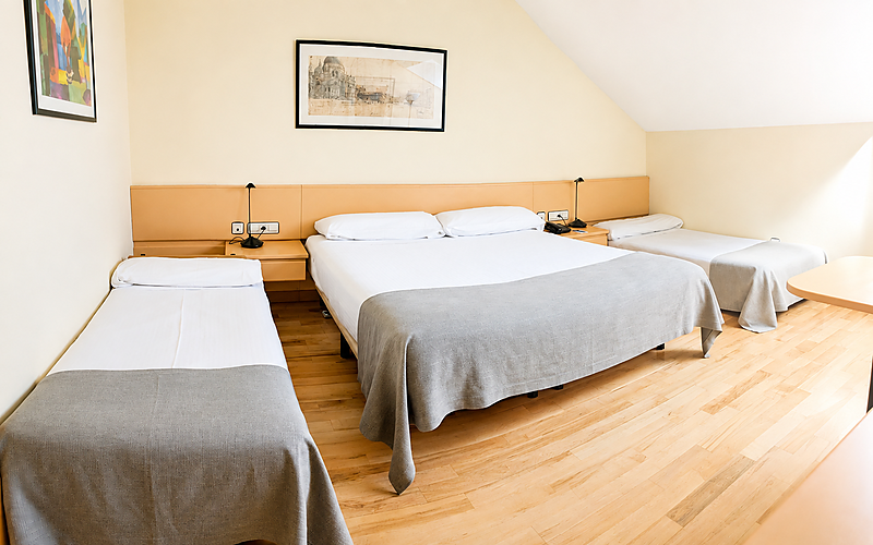 Amplia habitación de hotel con cama doble y dos individuales, ideal para familias que visitan Parquesur.