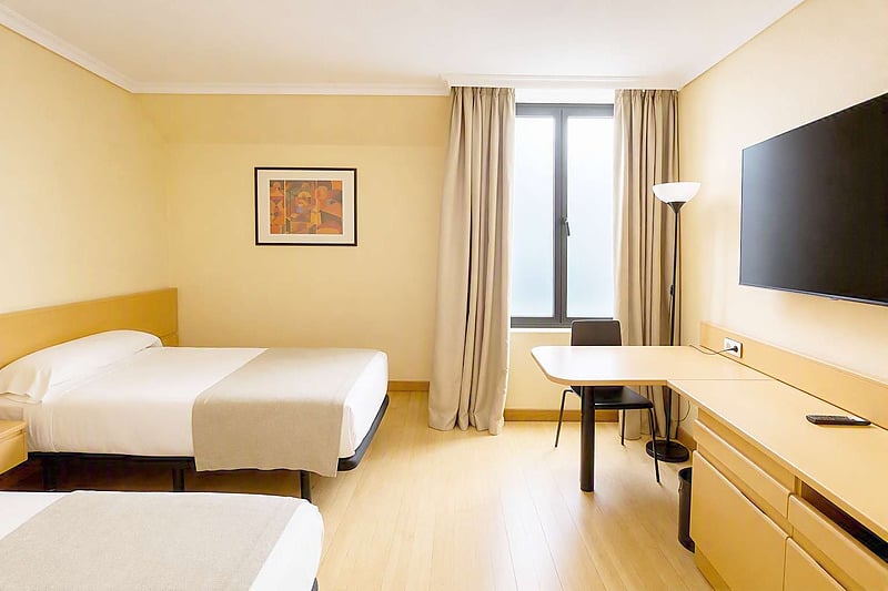Cómoda habitación de hotel con dos camas individuales, TV y escritorio. Ideal para su estancia cerca de AR: Parquesur.