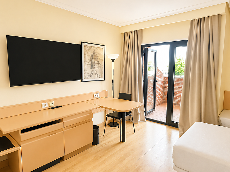 Spacious triple hotel room at AR: Parquesur with slanted ceiling, skylight, desk, and modern amenities.