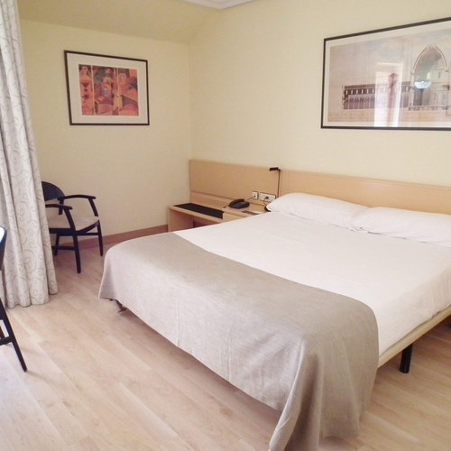 a hotel room with a large bed and two framed pictures on the wall