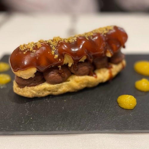 a pastry on a black plate with yellow sauce