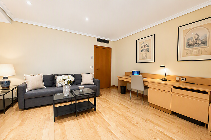 Modern studio hotel room near AR: Parquesur with comfortable bed, sofa, and light wood floors.