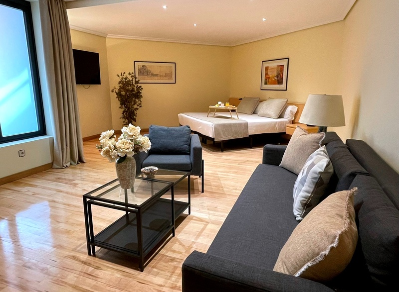 Modern studio hotel room near AR: Parquesur with comfortable bed, sofa, and light wood floors.