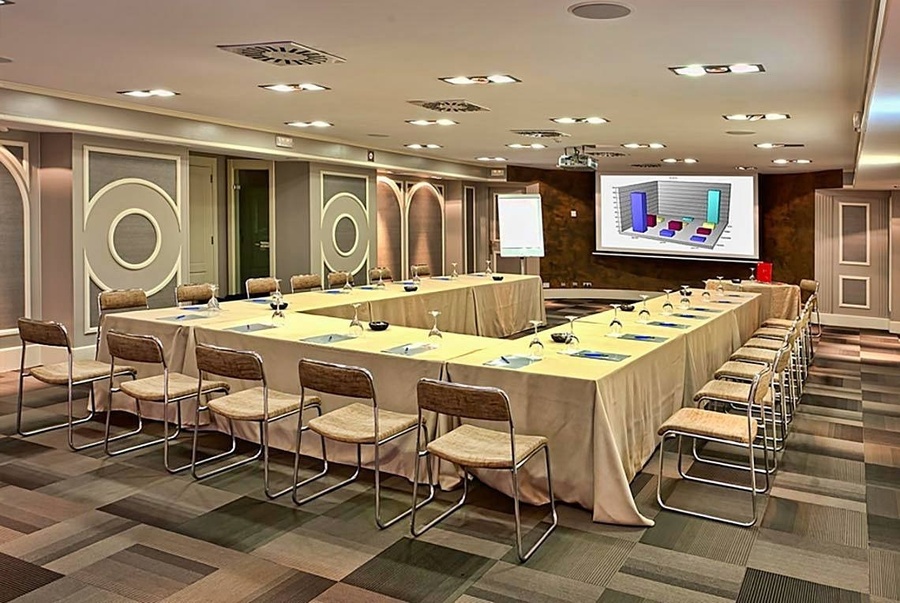 una sala de conferencias con mesas y sillas y una pantalla que muestra un gráfico