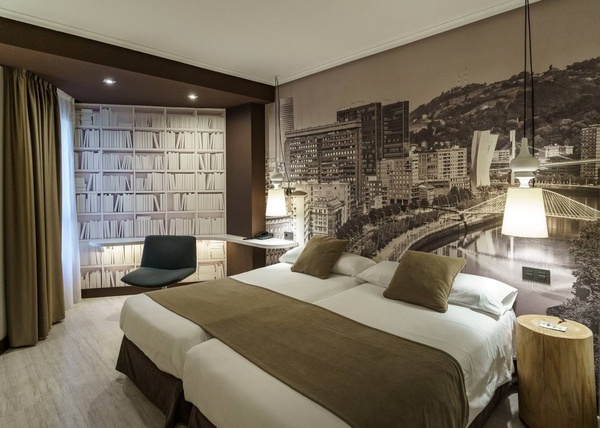una habitación de hotel con dos camas y un mural de una ciudad en la pared