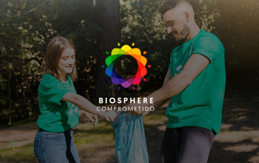 un hombre y una mujer recogen basura en un parque con el logo de biosphere comprometido en el fondo
