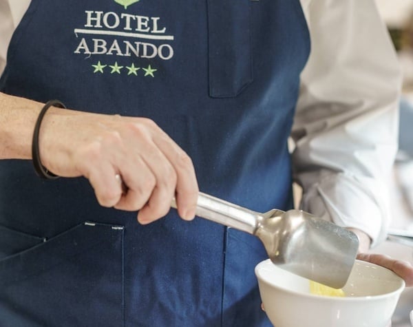 un hombre con un delantal azul que dice hotel abandono está mezclando algo en un tazón