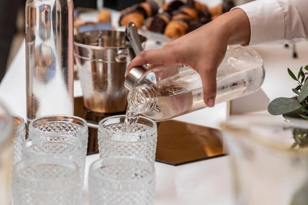 una persona vierte agua de una botella en un vaso