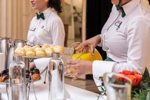 dos camareras en uniforme blanco están sirviendo comida en una mesa