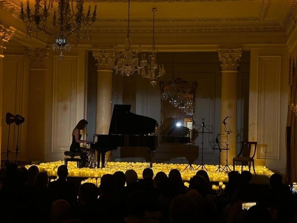 una mujer toca el piano en una habitación llena de velas