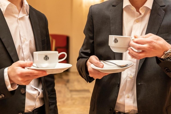 dos hombres en trajes sostienen tazas de café en sus manos