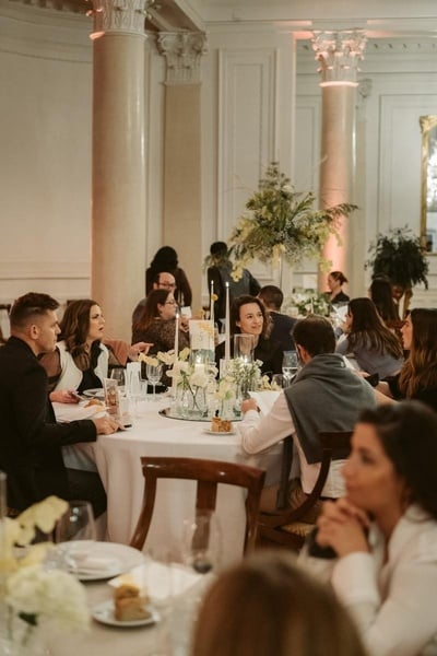 un grupo de personas están sentadas en mesas con platos y copas de vino