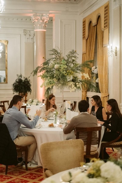 un grupo de personas se sienta alrededor de una mesa en una habitación decorada con flores