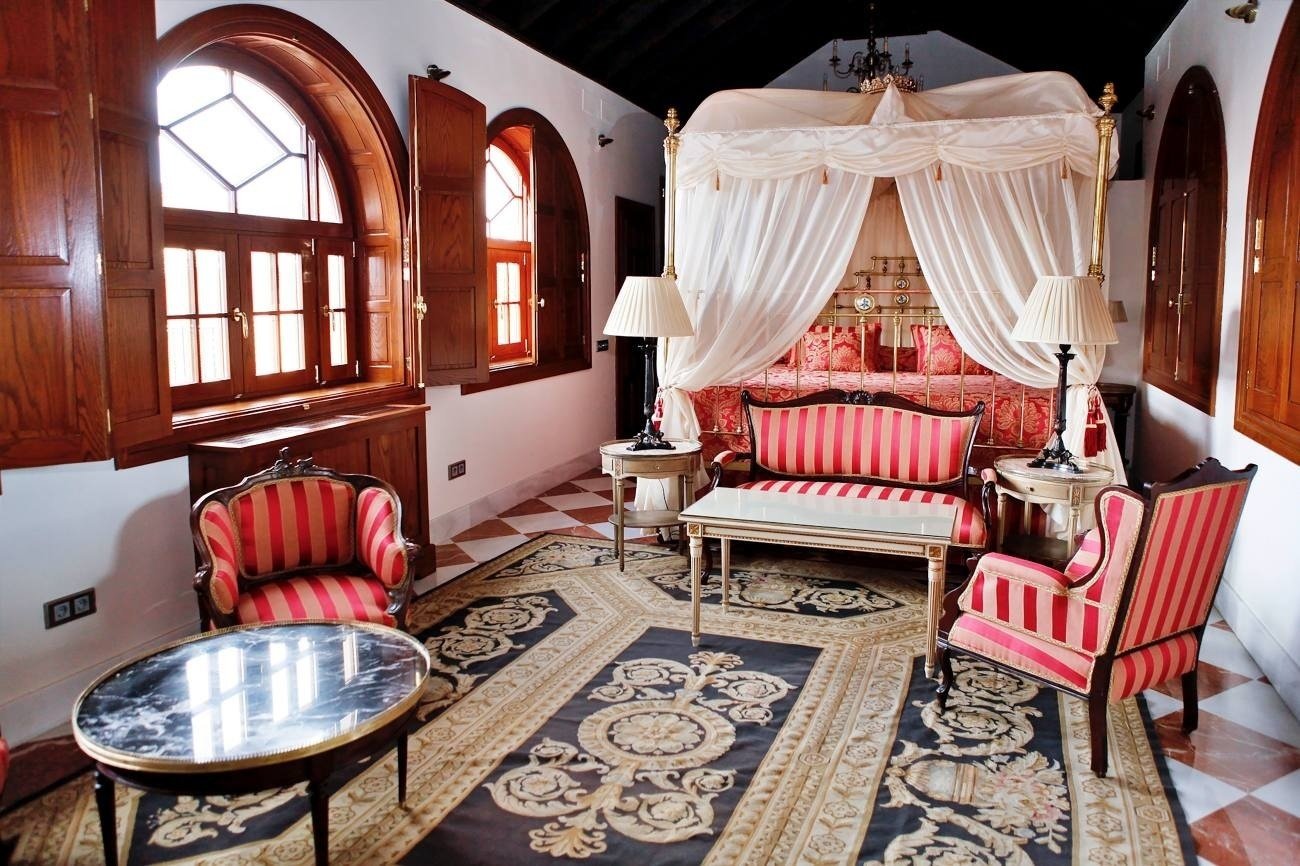 una habitación con una cama con dosel y un sofá a rayas rojas y blancas
