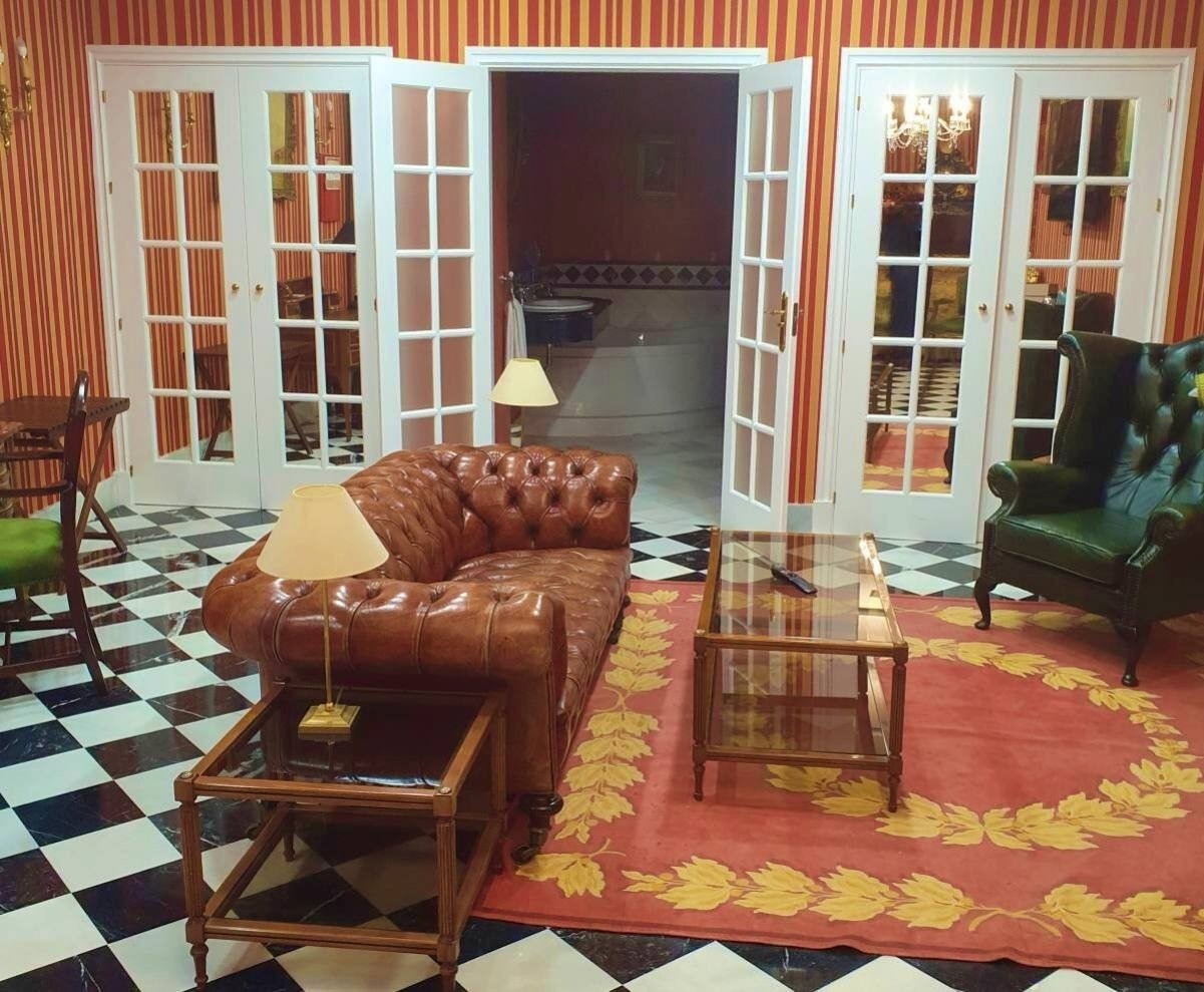 a living room with a brown leather couch and green chairs