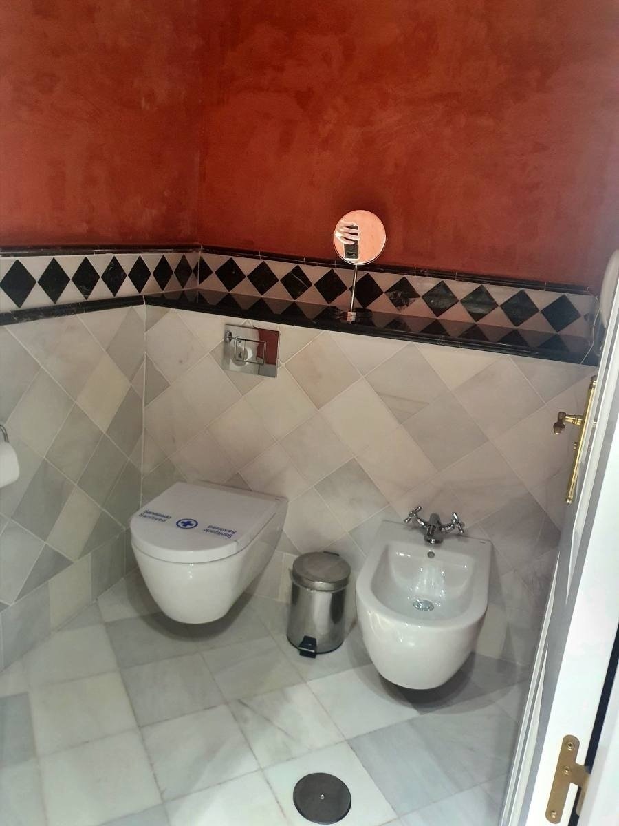 a bathroom with two toilets and a bidet