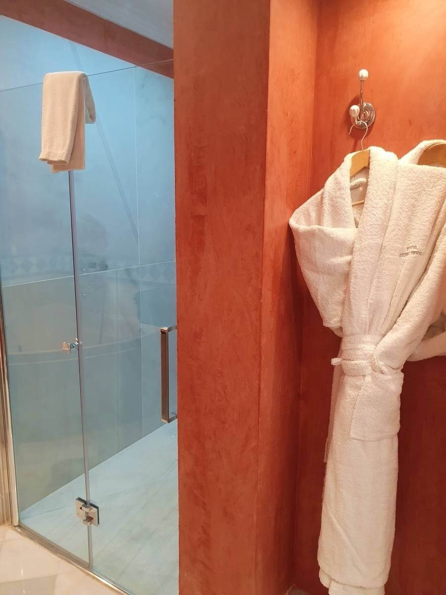 una bata blanca está colgada en un cuarto de baño junto a una puerta de vidrio