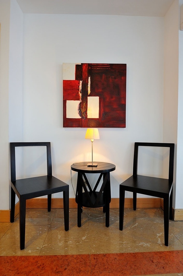 dos sillas y una mesa con una lámpara y un cuadro en la pared