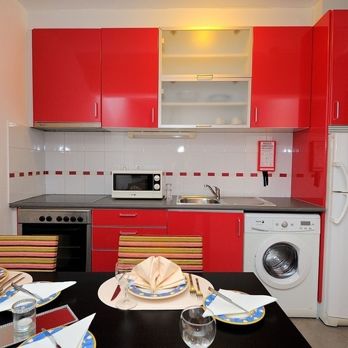 a kitchen with red cabinets and a white refrigerator