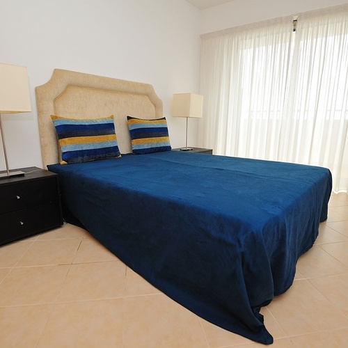 a bedroom with a blue bed and two nightstands