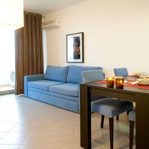 a living room with a blue couch and a dining table