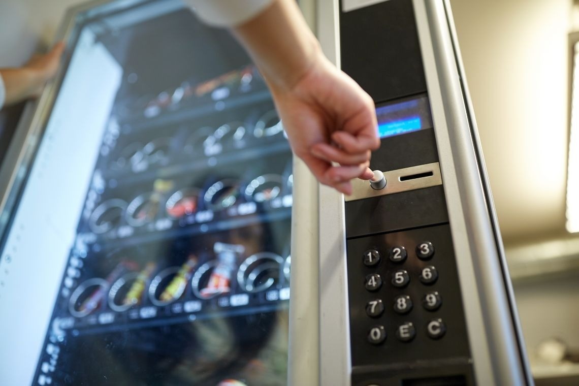 una persona presiona un botón en una máquina expendedora