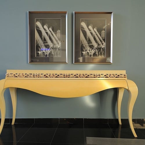 a yellow table with two framed pictures on the wall above it