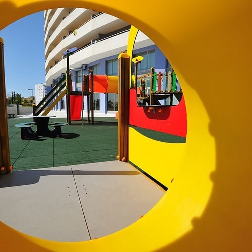 a view of a playground through a yellow tube