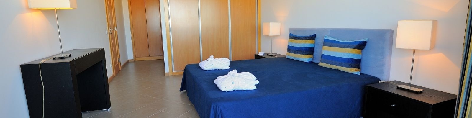 un dormitorio con una cama azul y almohadas a rayas
