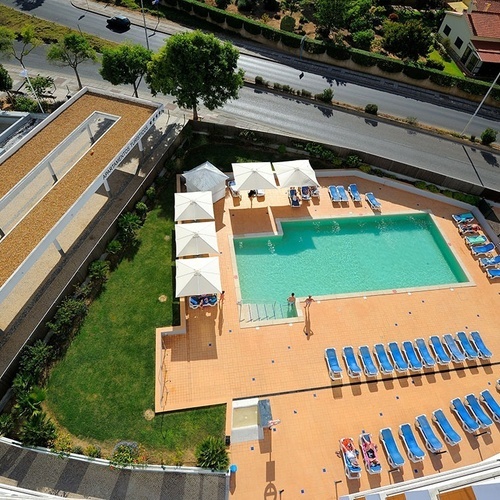 an aerial view of a large swimming pool surrounded by chairs and umbrellas