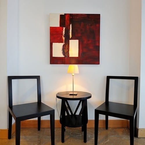 two chairs and a table in front of a painting on the wall