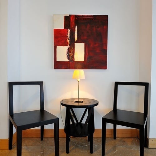 duas cadeiras e uma mesa com uma pintura vermelha sobre a parede