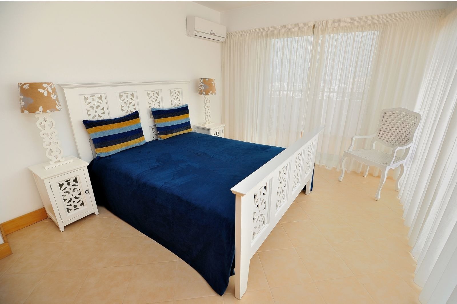 une chambre avec un lit bleu et une chaise blanche