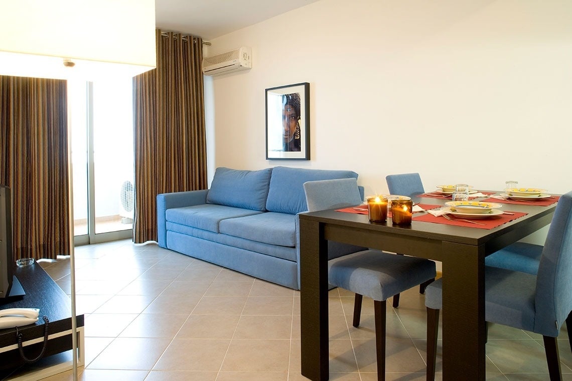 a living room with a blue couch and a dining table