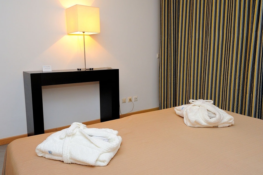 una habitación con una lámpara y albornoz en la cama