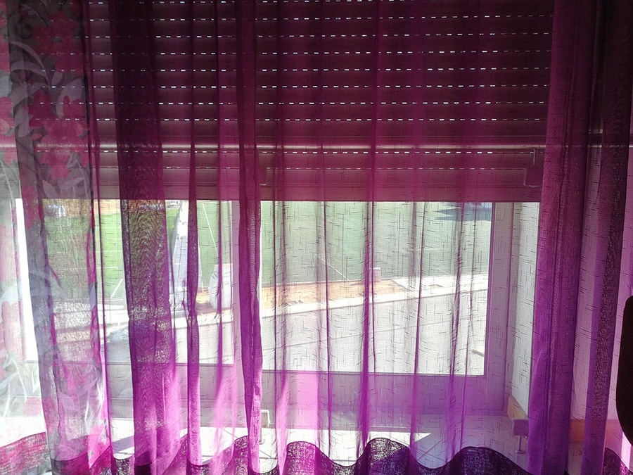 una ventana con cortinas moradas y una persiana enrollable