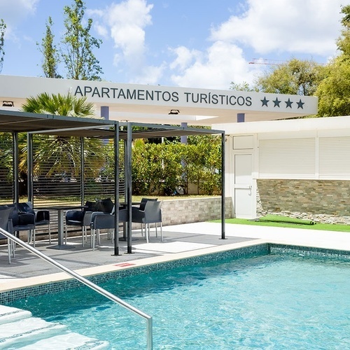 uma piscina ao lado de um prédio que diz apartamentos turisticos