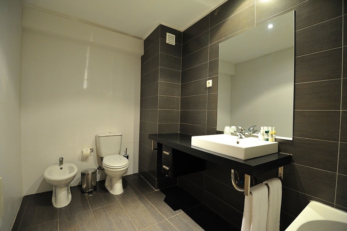 a bathroom with a sink toilet and bidet