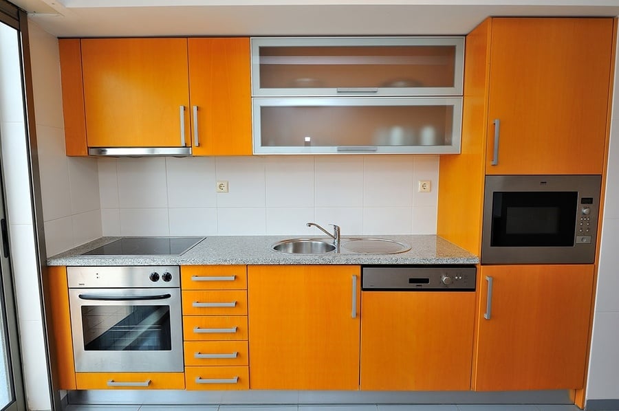 una cocina con gabinetes naranjas y electrodomésticos de acero inoxidable