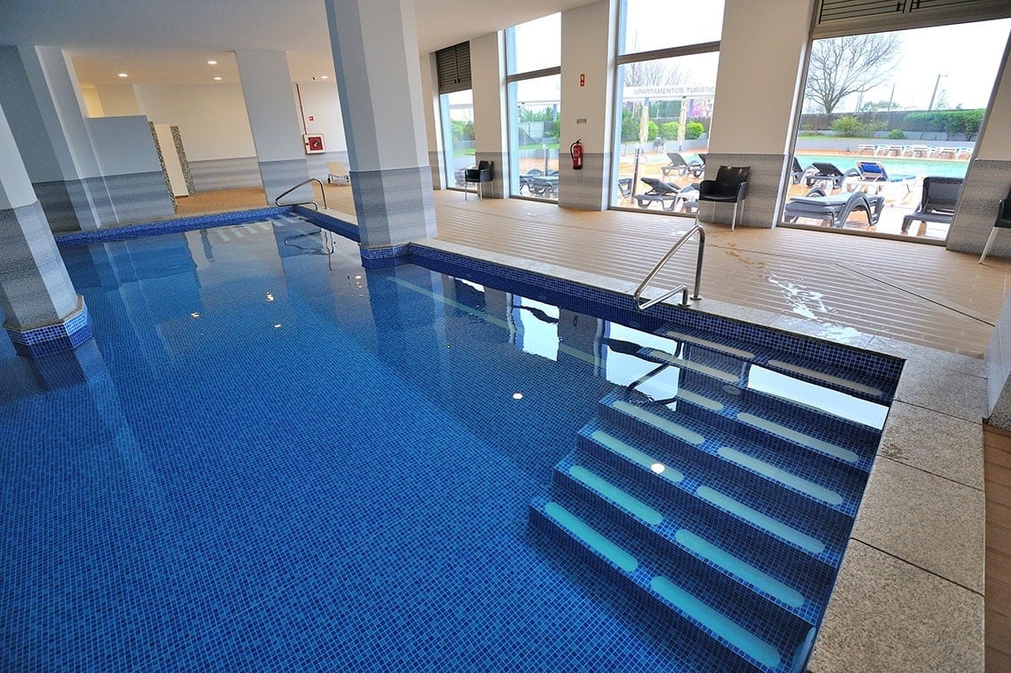 a large indoor swimming pool with blue tiles and stairs