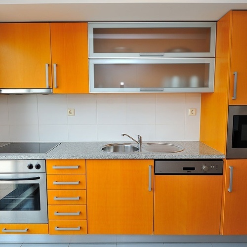 a kitchen with orange cabinets and stainless steel appliances