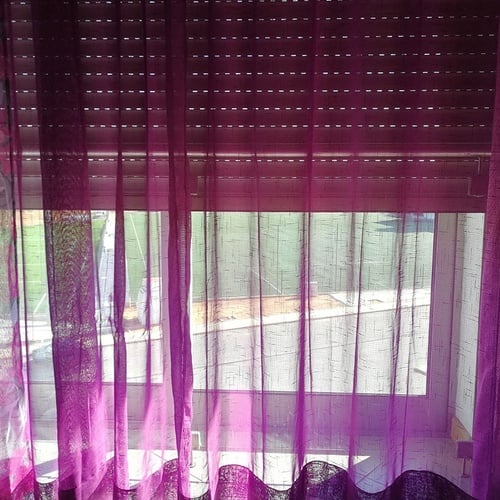 a window with purple curtains and a shutter