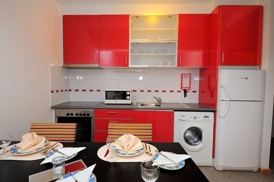 una cocina con gabinetes rojos y electrodomésticos blancos