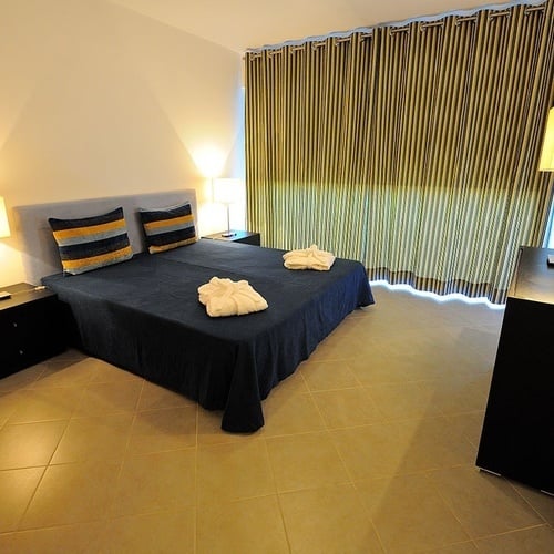 a bedroom with a blue bed and striped curtains