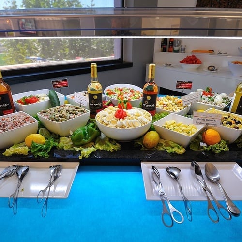 a variety of salads and bottles of wine on a table