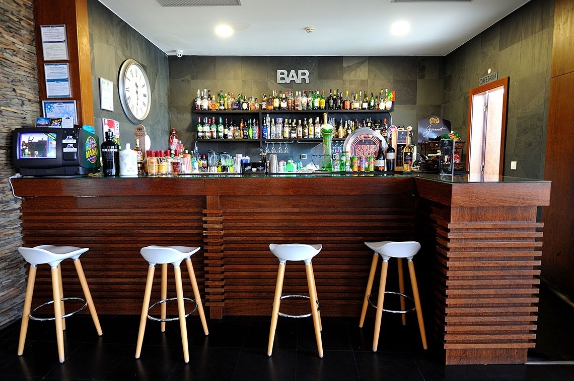 un bar avec un comptoir en bois et des tabourets blancs