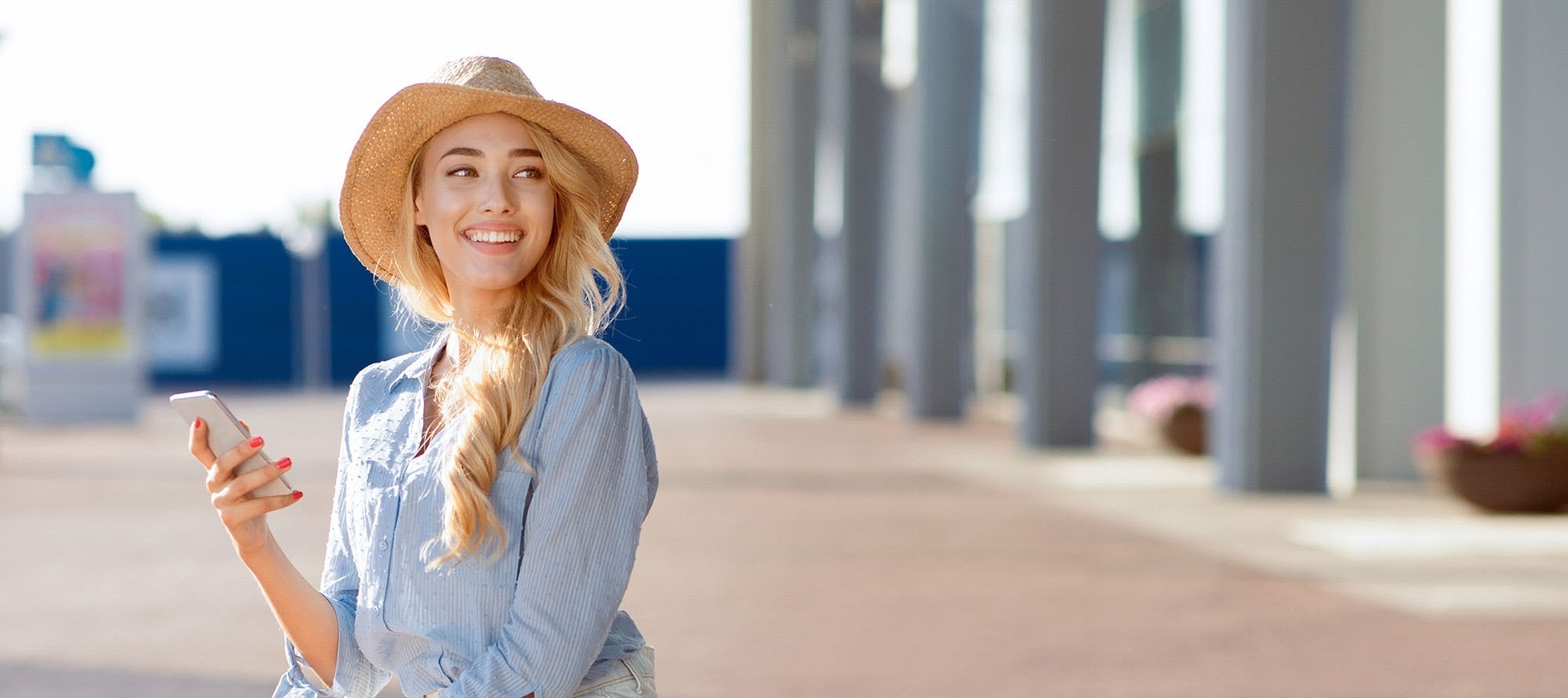 a woman wearing a straw hat is holding a cell phone