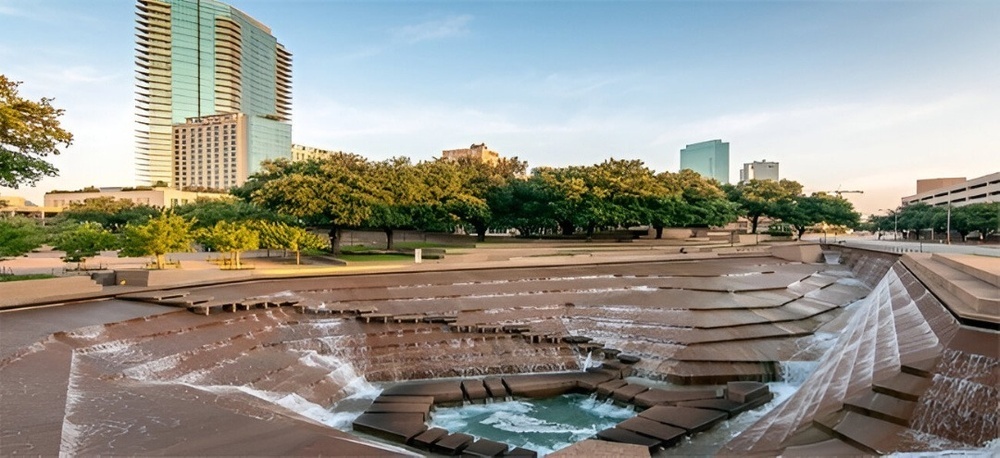 a waterfall in a park with a building in the background