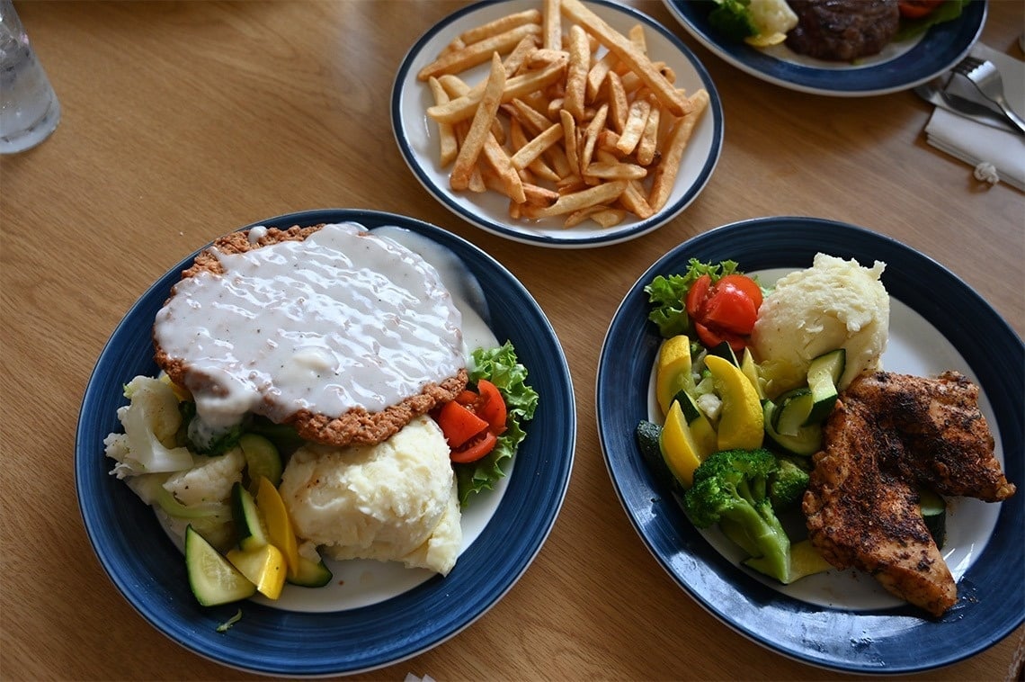 two plates of food with french fries and mashed potatoes on a table